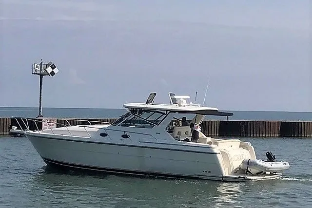 Slide: The Image of 1997 Tiara Yachts 4000 Express cruising near a harbor with clear skies. - 1