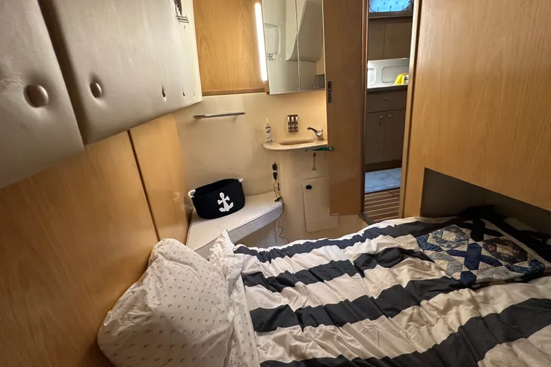 Slide: The Image of Cozy cabin interior of 1997 Tiara Yachts 4000 Express with striped bedding and wooden accents. - 27