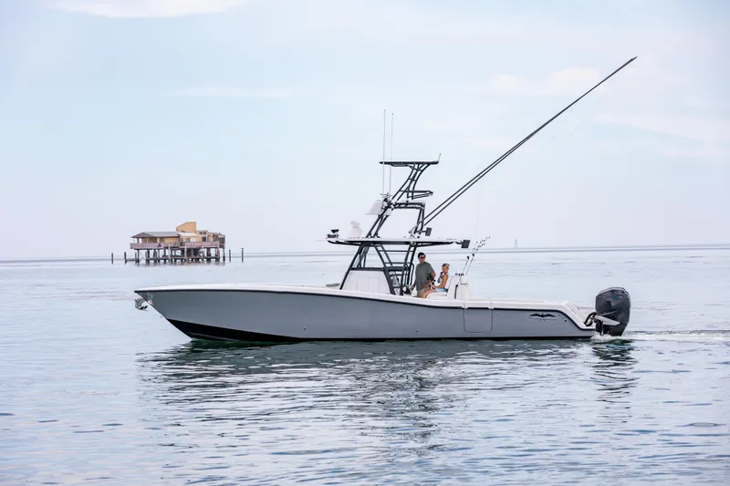 Slide: The Image of 2021 Invincible 39 Open Fisherman boat cruising on calm waters near a stilt house. - 65