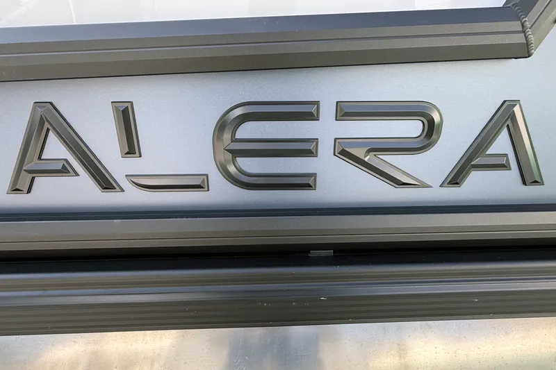 Slide: The Image of Close-up of Alera M25L 2027 logo on metallic surface. - 2