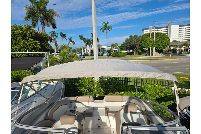 Slide: The Image of 2011 Yamaha Boats 242 Limited with canopy, parked near palm trees and buildings. - 12