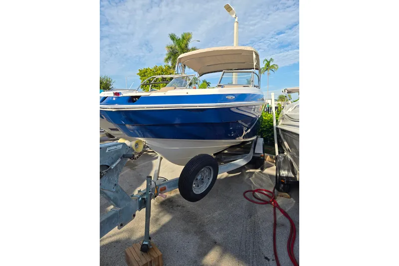 The Image of 2011 Yamaha Boats 242 Limited on trailer, blue hull, parked outdoors under clear sky. - 0