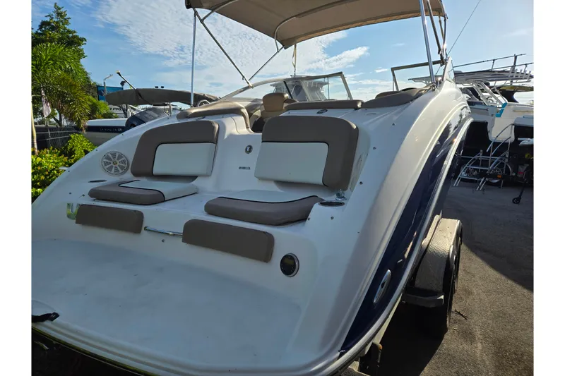 Slide: The Image of 2011 Yamaha Boats 242 Limited with cushioned seating and canopy, parked outdoors. - 3