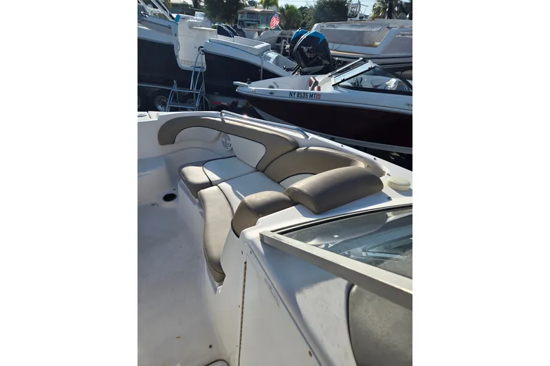Slide: The Image of 2011 Yamaha Boats 242 Limited interior seating, featuring comfortable, stylish design in a marina setting. - 9