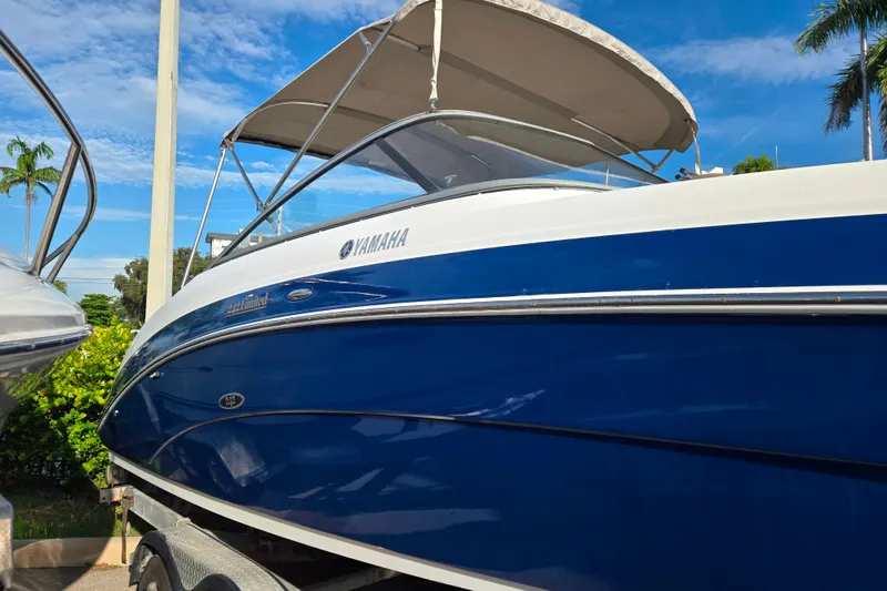 Slide: The Image of 2011 Yamaha Boats 242 Limited, blue and white, docked under clear sky. - 2