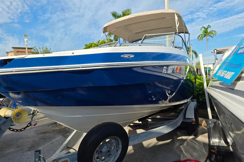 Slide: The Image of 2011 Yamaha Boats 242 Limited in blue, parked on a trailer under a clear sky. - 1