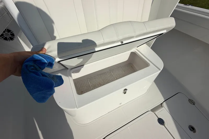 Slide: The Image of Open storage compartment on 2024 Bluewater BW 25T boat, with a person holding a blue cloth. - 49