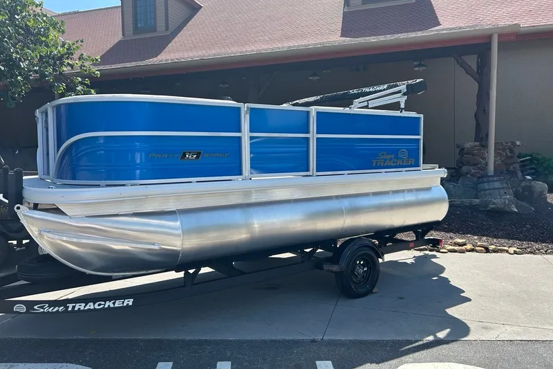 The Image of 2027 Sun Tracker Party Barge 16 DLX pontoon boat on trailer, parked outdoors. - 0