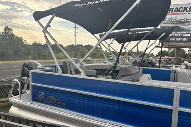 The Image of 2027 Sun Tracker Party Barge 18 DLX pontoon boat with canopy, parked outdoors. - 0