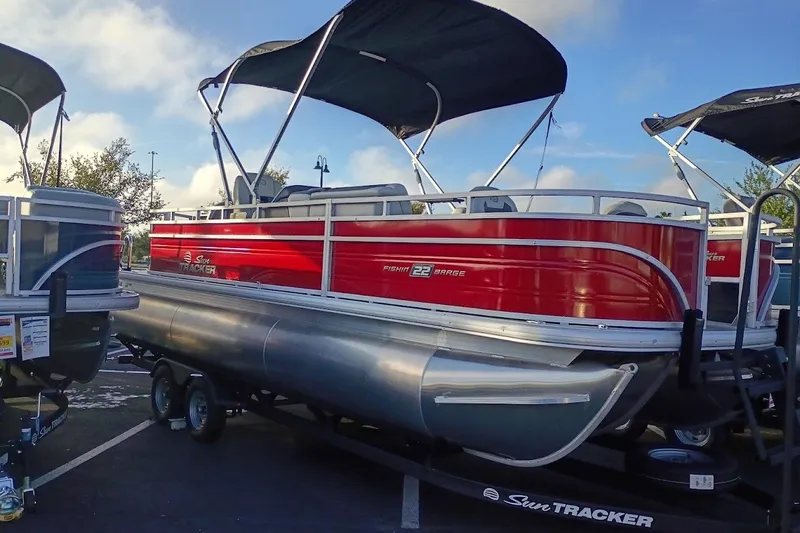 The Image of 2027 Sun Tracker Fishin' Barge 22 DLX pontoon boat with red exterior and canopy. - 0