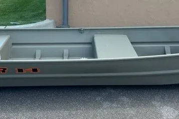 The Image of 2027 Tracker Grizzly 14 Jon boat on pavement near a building. - 0