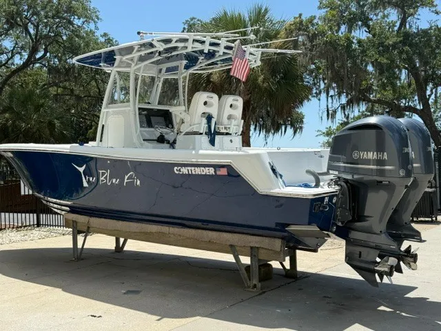 Slide: The Image of A 2020 Contender 28 Sport boat with a blue hull and twin Yamaha engines on a trailer. - 1