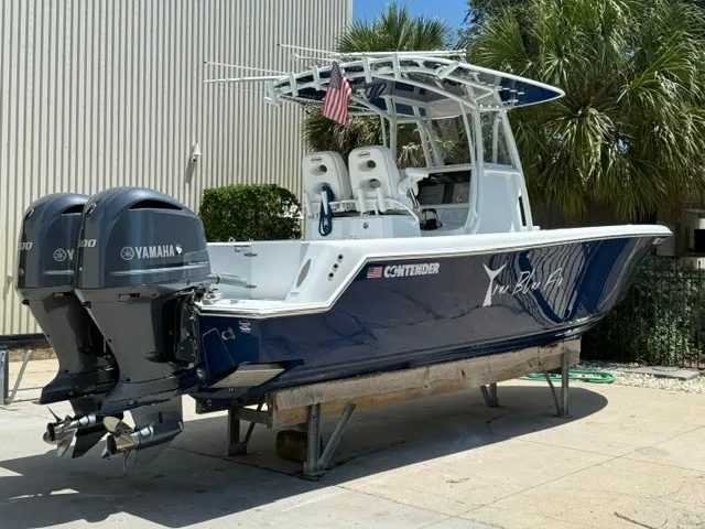 Slide: The Image of A 2020 Contender 28 Sport boat with twin Yamaha engines, on a stand outdoors. - 3