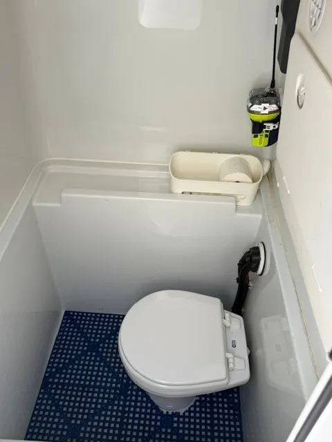 Slide: The Image of The image shows a compact boat toilet with a white toilet and blue floor mat. - 11