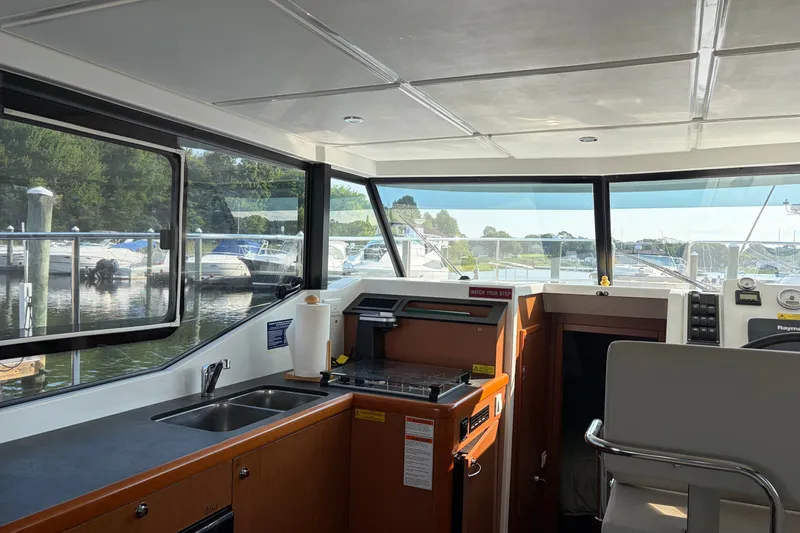 Slide: The Image of Interior of 2017 Beneteau Swift Trawler 30 with kitchen and helm, docked at marina. - 30