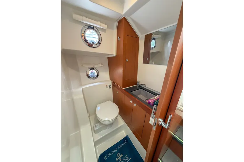 Slide: The Image of Bathroom interior of 2017 Beneteau Swift Trawler 30 with porthole and wooden cabinetry. - 54