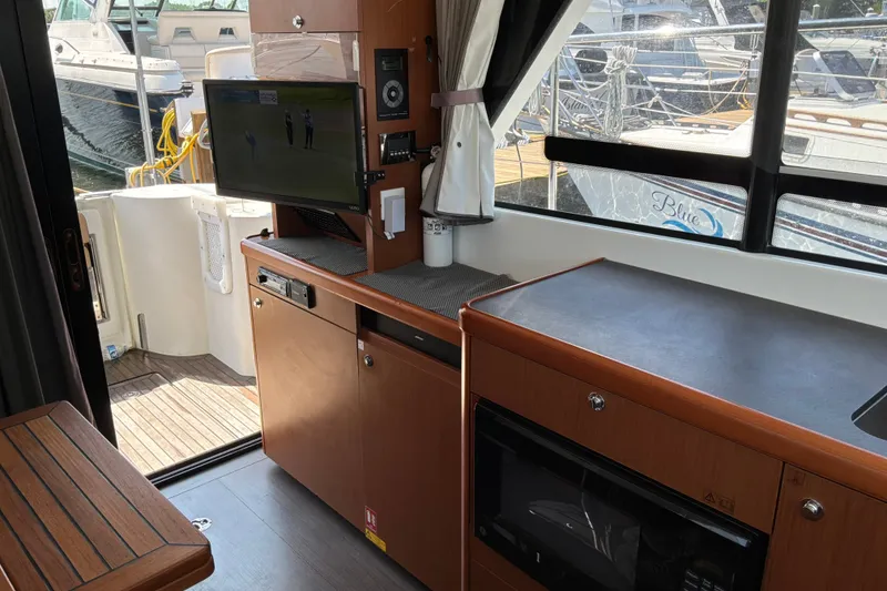 Slide: The Image of Interior of 2017 Beneteau Swift Trawler 30 with TV, kitchenette, and marina view. - 23