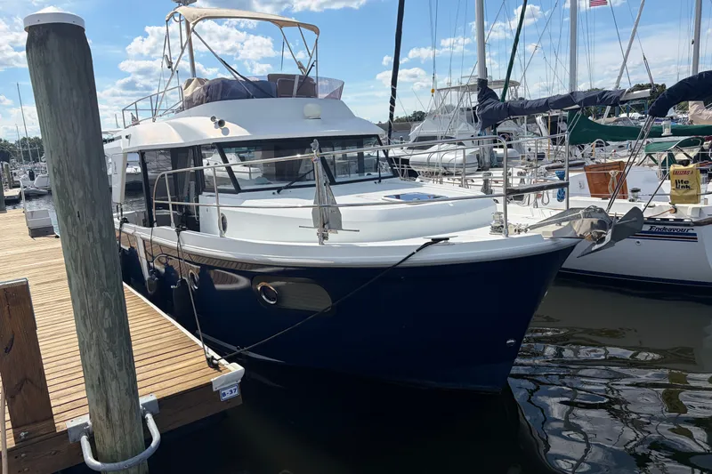 The Image of 2017 Beneteau Swift Trawler 30 docked at marina under clear blue sky. - 1