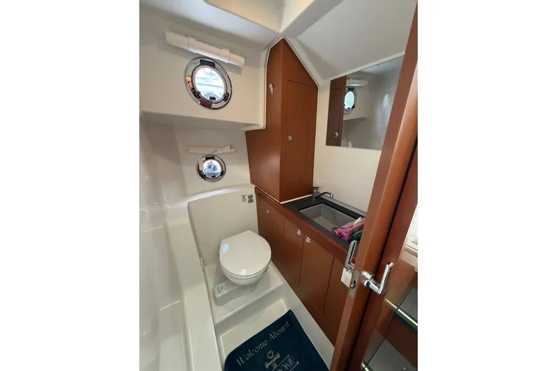 Slide: The Image of Bathroom interior of 2017 Beneteau Swift Trawler 30 with porthole and wooden cabinetry. - 40