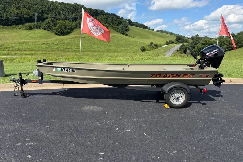 The Image of 2025 Tracker Grizzly 1436 boat on trailer with Mercury motor, parked on asphalt. - 0