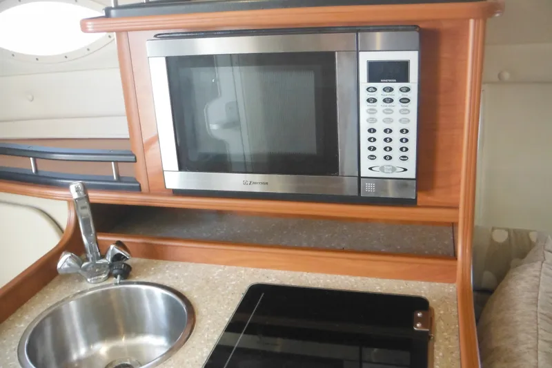 Slide: The Image of 2005 Rinker Fiesta Vee 250 galley with microwave, sink, and stove. - 31