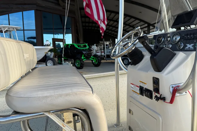 Slide: The Image of 2015 Xpress H24 Bay boat interior with steering console and seating, American flag in background. - 18
