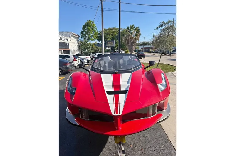 The Image of Red 2026 Watersports Car JetCar with white racing stripes, parked outdoors. - 1