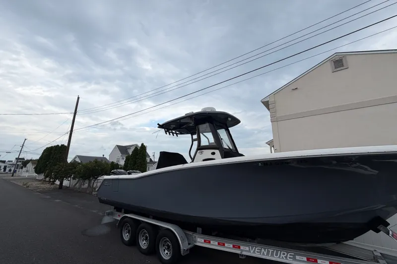 The Image of 2023 Tidewater 282 CC Adventure Bluewater boat on trailer, parked on residential street. - 0