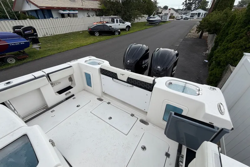 Slide: The Image of 2023 Tidewater 282 CC Adventure Bluewater boat with dual Yamaha engines, docked in a residential area. - 20