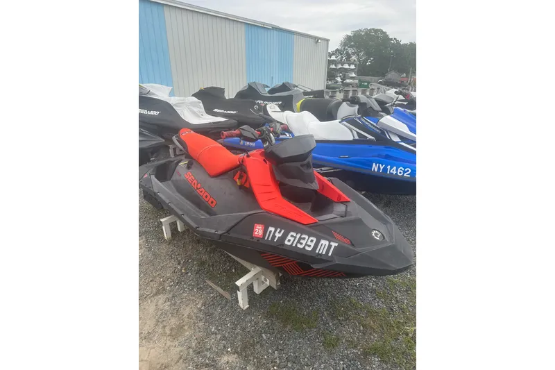 Slide: The Image of 2022 Sea-Doo Spark Trixx jet ski in red and black, parked outdoors. - 7