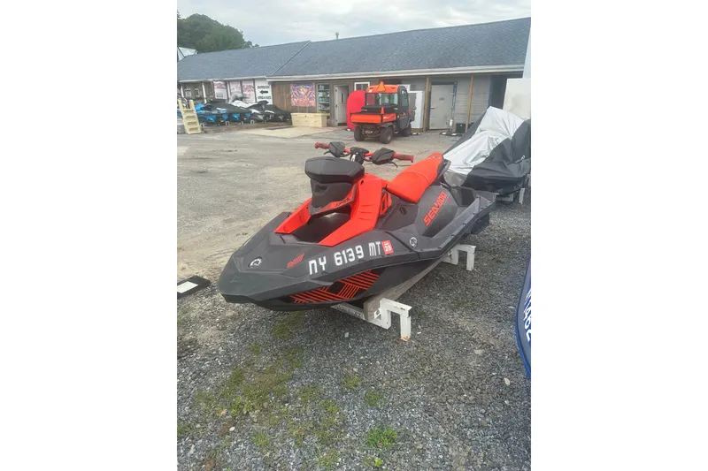 The Image of 2022 Sea-Doo Spark Trixx jet ski in a dealership lot, vibrant red and black design. - 1