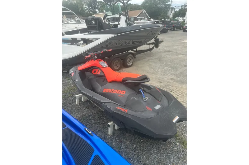 Slide: The Image of 2022 Sea-Doo Spark Trixx jet ski in vibrant red, parked outdoors. - 4