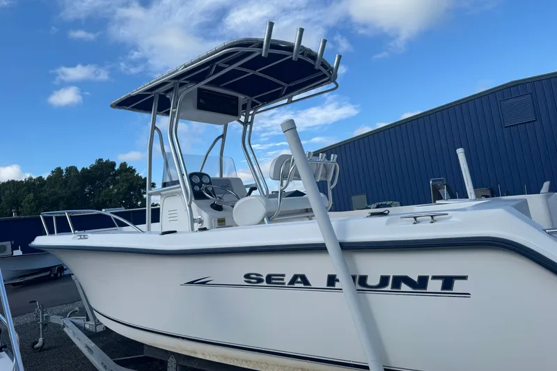 Slide: The Image of 2005 Sea Hunt Triton 220 boat with T-top, parked outdoors under blue sky. - 1