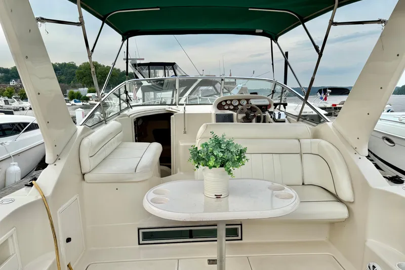 Slide: The Image of 1999 Monterey 296 Cruiser interior with white seating, table, and green canopy at marina. - 1