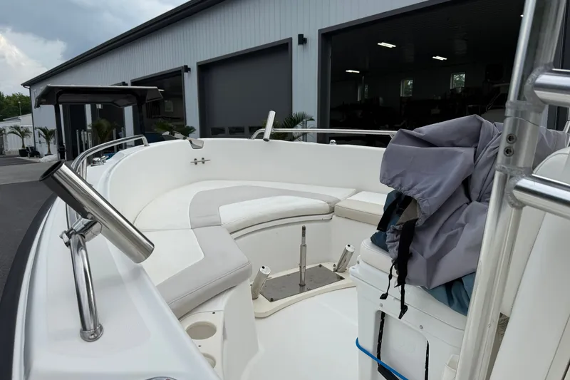 Slide: The Image of 2006 Boston Whaler 210 Outrage boat interior with seating and storage, parked near a building. - 9