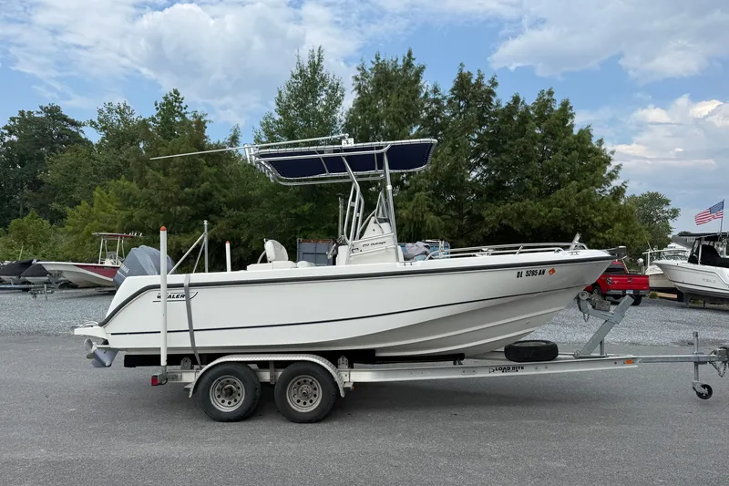 The Image of 2006 Boston Whaler 210 Outrage boat on trailer, parked outdoors with trees in background. - 1