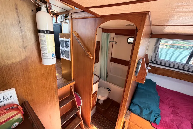 Slide: The Image of 1979 Marine Trader 36 interior with wooden finish, showing a compact bathroom and cozy sleeping area. - 18