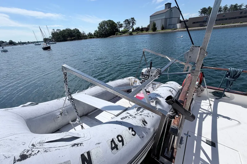 Slide: The Image of 1979 Marine Trader 36 with dinghy on deck, moored in a scenic harbor. - 36