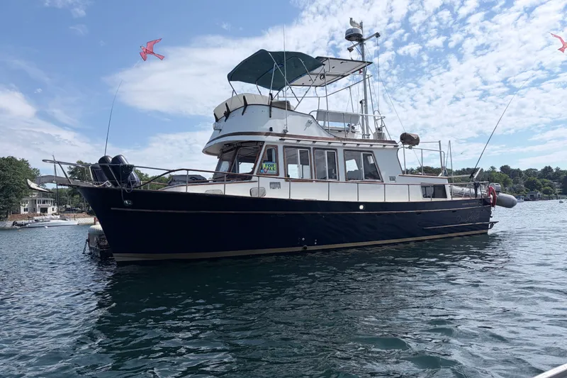 The Image of 1979 Marine Trader 36 yacht on water, clear sky, "For Sale" sign visible. - 1