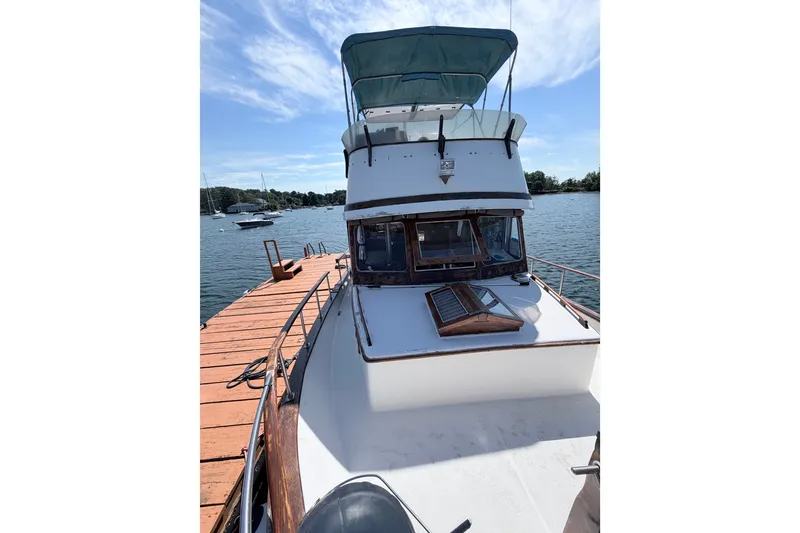 Slide: The Image of 1979 Marine Trader 36 yacht docked by a wooden pier under a clear blue sky. - 26