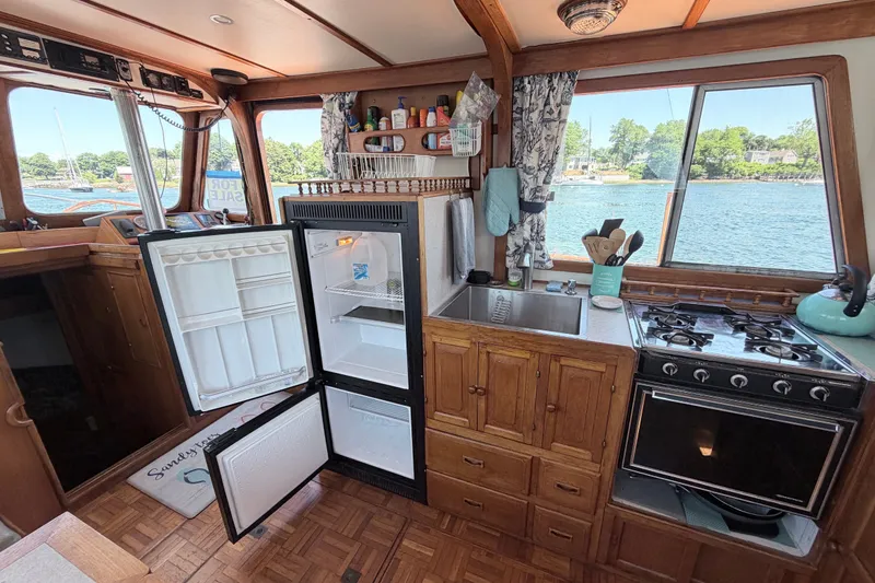 Slide: The Image of 1979 Marine Trader 36 interior kitchen with open fridge, stove, and scenic window view. - 48