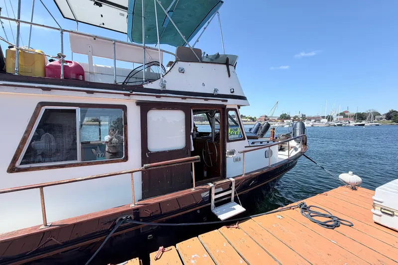 Slide: The Image of 1979 Marine Trader 36 yacht docked, "For Sale" sign visible, sunny day, calm waters. - 31