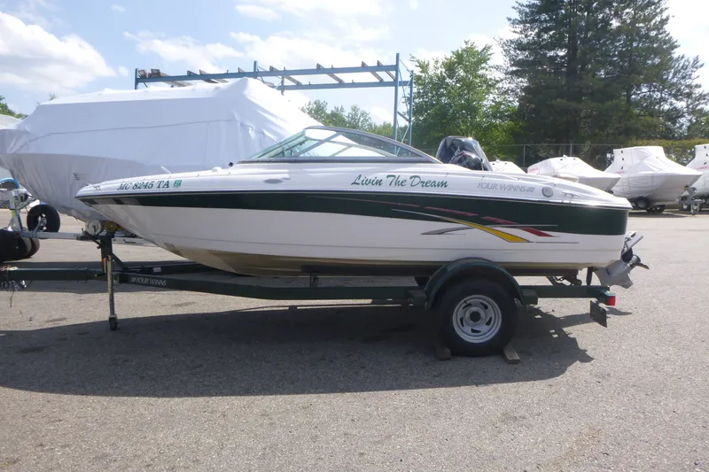 The Image of 2007 Four Winns 180 Horizon boat on trailer, parked outdoors under clear sky. - 1