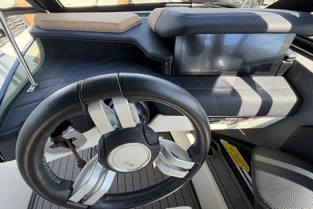 Slide: The Image of 2022 Nautique Super Air Nautique G25 dashboard with modern steering and touchscreen display. - 24