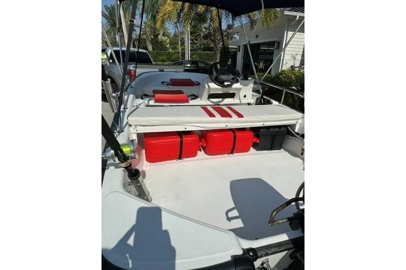 Slide: The Image of 2000 Boston Whaler Sport 13 boat interior with red storage containers and steering wheel. - 10
