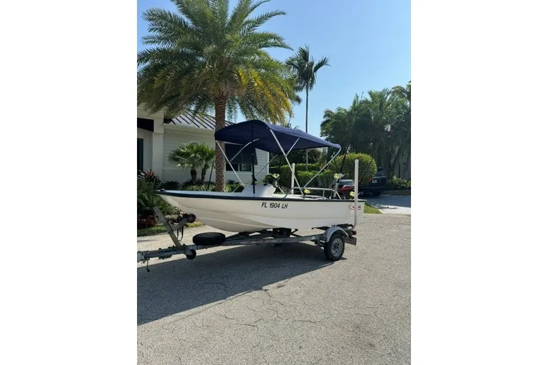 Slide: The Image of 2000 Boston Whaler Sport 13 boat on trailer, parked near palm trees. - 7
