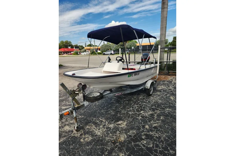 Slide: The Image of 2000 Boston Whaler Sport 13 boat on trailer with canopy, parked outdoors. - 5