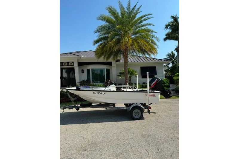 Slide: The Image of 2000 Boston Whaler Sport 13 boat on trailer, parked near palm trees and house. - 12