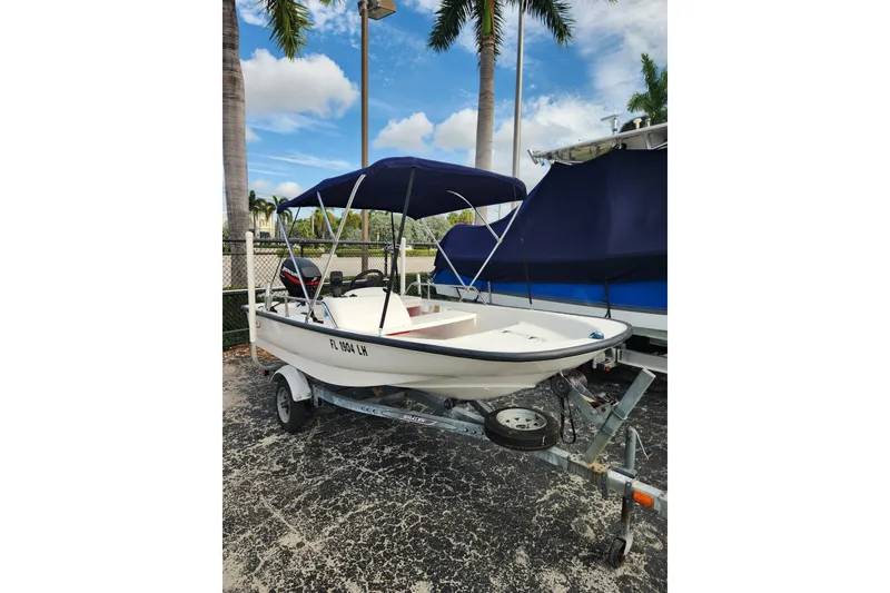 Slide: The Image of 2000 Boston Whaler Sport 13 boat on trailer with canopy, parked outdoors. - 4