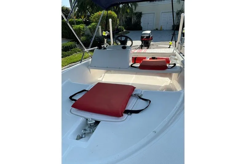 Slide: The Image of 2000 Boston Whaler Sport 13 boat interior with red cushions and steering console. - 9